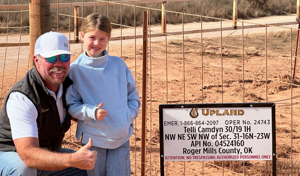 A man and a child give thumbs up near a fenced area.