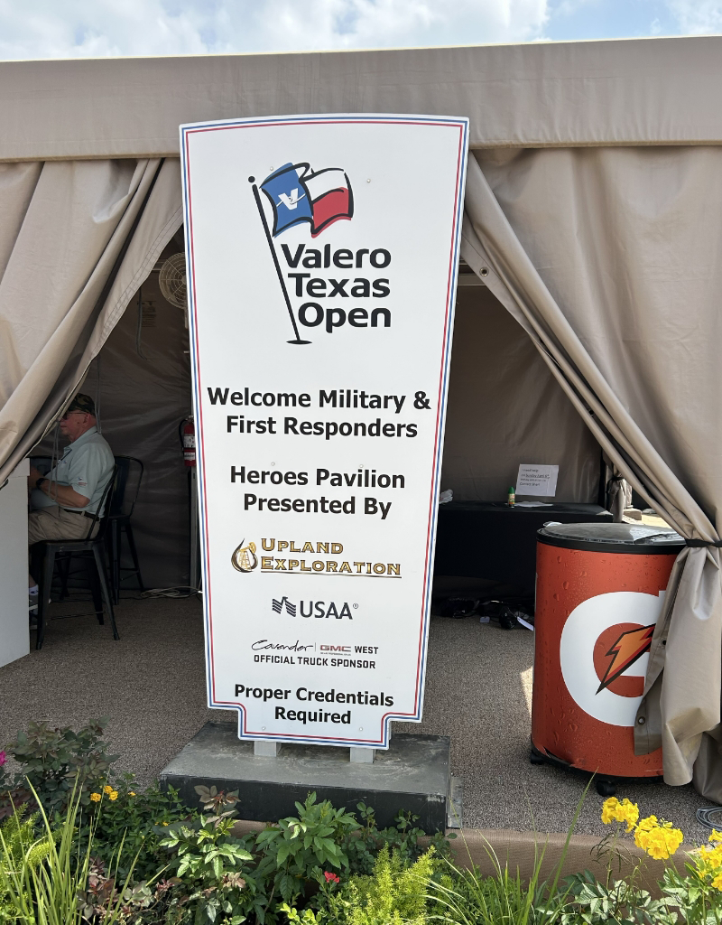 Sign reading "Valero Texas Open Welcome Military & First Responders" outside a tent, with sponsor logos. Proper credentials required.